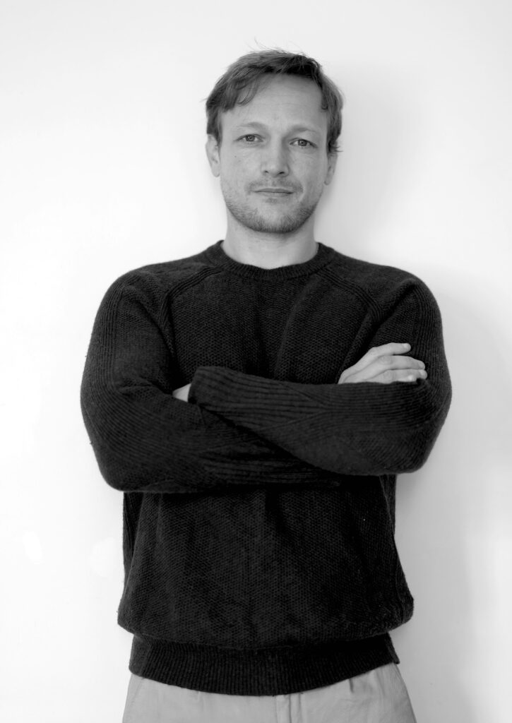 Photo portrait en noir et blanc d'un homme, coach en séduction, debout les bras croisés